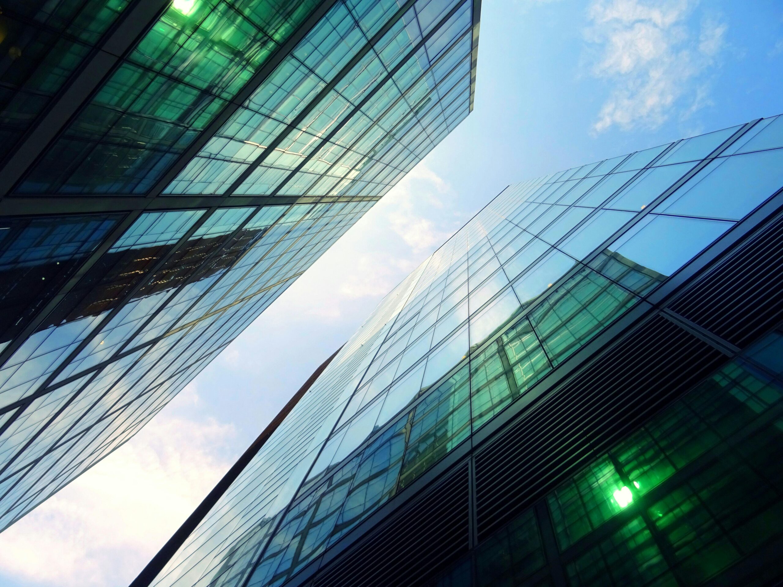 view between two green glass sky scrapers to a blue sky like the city center of Eindhoven where the Holland Expat Center South is